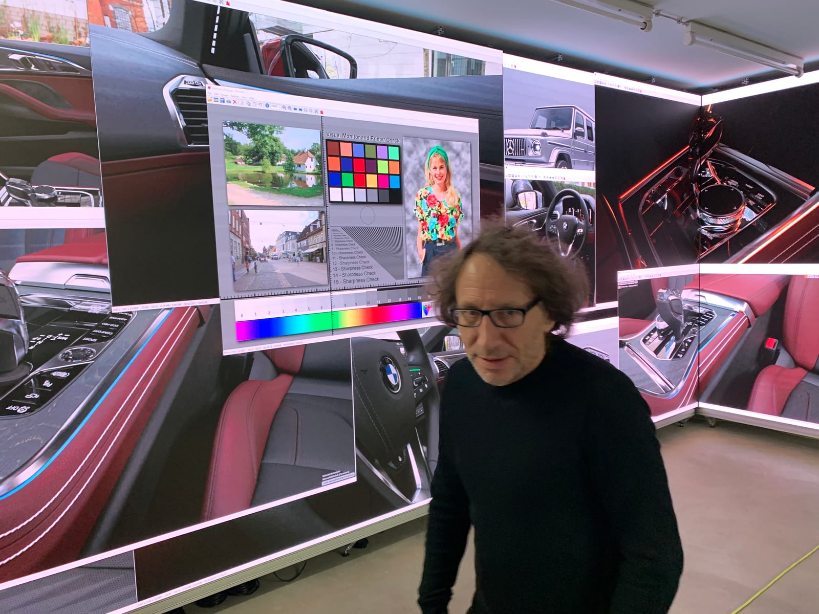 TRUE Performance team member in front of a TRUE dvLED wall showing a BMW interior beside a color reference chart at the Experience Center in Kassel, Germany